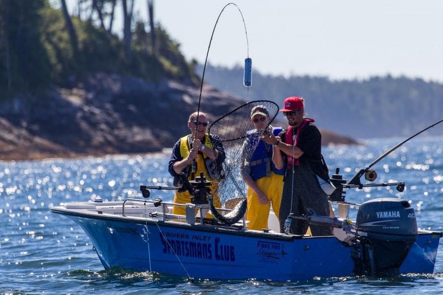 guided-fishing-2021 While in their boat with the ocean sparkling all around them two guests at Rivers Inlet Sportsman's Club are thrilled as their guide assists them in netting their BC salmon catch of the day!