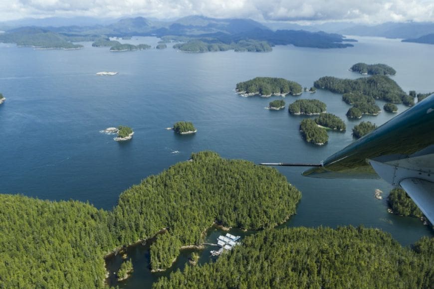 sportsmansclubjr150726-018 Aerial view of the Rivers Inlet Sportsman's Club fishing lodge taken from inside the plane. You can see the wing tip and it dips down to begin it's landing.